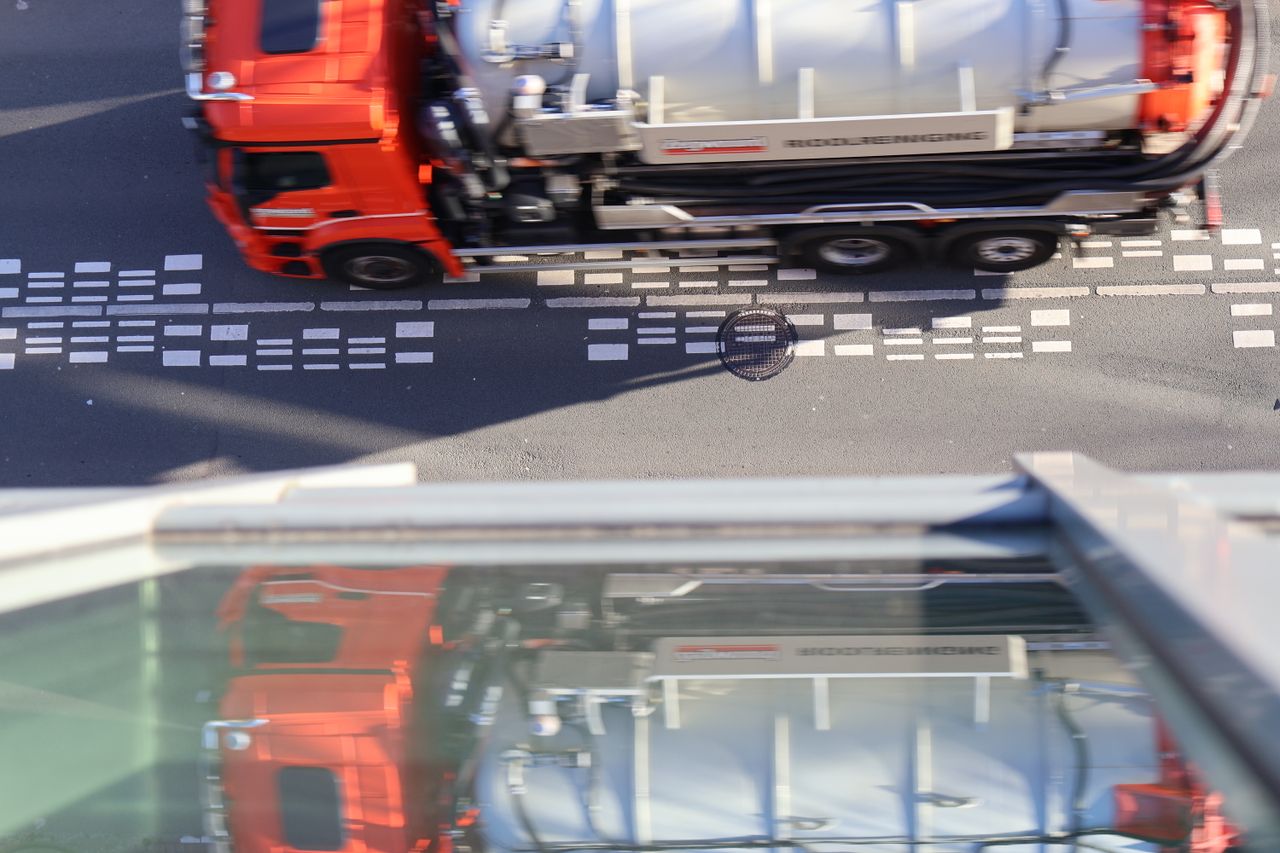 A vibrant red truck navigates a crosswalk in Amsterdam, captured from above.
